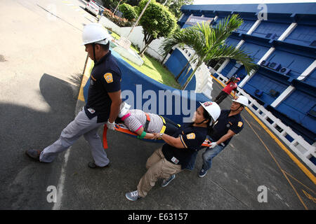 Quezon City, Filippine. 13 Ago, 2014. Soccorritori eseguire la simulazione di una vittima durante un terremoto trapano in Quezon City, Filippine, e il agosto 13, 2014. Il terremoto trapanare mira a valutare la preparazione alle situazioni di emergenza le capacità di polizia. Credito: Rouelle Umali/Xinhua/Alamy Live News Foto Stock