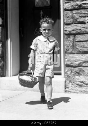 1930s BOY IL TRASPORTO DI LIBRI cestino pranzo che indossano pantaloncini OUTFIT ETON collare andando a scuola di mattoni casa di pietra Foto Stock