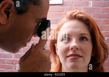 Anni Novanta African American oculista esaminando Occhi di donna close-up Foto Stock