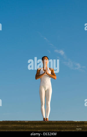 Giovane donna pratica di Hatha yoga, all'aperto, che mostra la posa, Tadasana Pranamasana, posa di preghiera Foto Stock