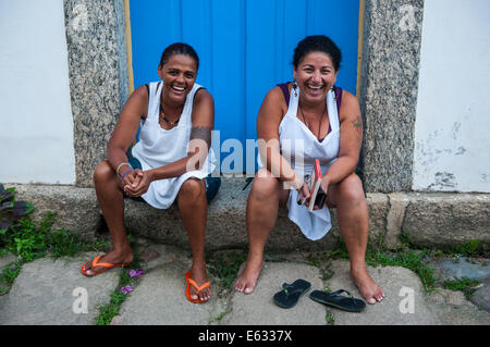 Due donne amichevole seduti sulla soglia di casa, Paraty, Stato di Rio de Janeiro, Brasile Foto Stock