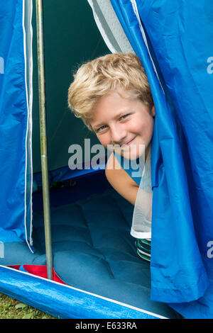 Un ragazzo, 10 anni, guardando fuori dalla sua tenda Foto Stock