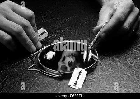 Mani tenendo la lama di un rasoio e arrotolato a $20.00 BILL OLTRE LO SPECCHIO COPERTO CON LA COCAINA E LA RIFLESSIONE DI MORTE teschio di testa Foto Stock