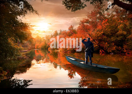 Un uomo in una barca sul fiume in autunno Foto Stock