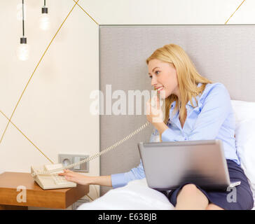 Imprenditrice con il computer portatile e il telefono in camera di albergo Foto Stock