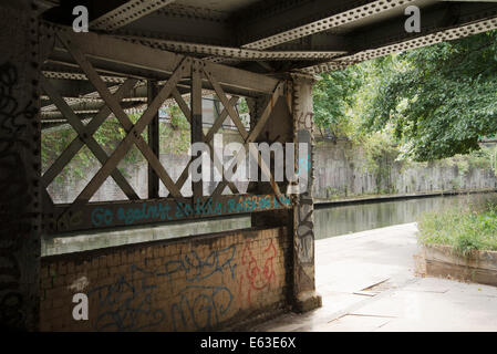 Graffiti "andare contro la società' sulla parete e di elementi in ferro battuto del ponte sul Regents Canal Foto Stock