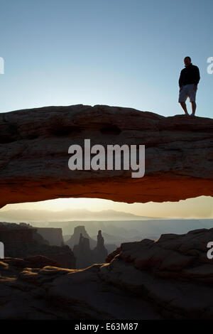 Persona sulla Mesa Arch e sunrise oltre La Sal Mountains, il Parco Nazionale di Canyonlands, Utah, Stati Uniti d'America Foto Stock