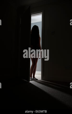 Irriconoscibile silhouette di una ragazza in piedi in una porta. Foto Stock