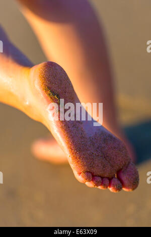 Sandy piedini femmina sulla spiaggia dal tramonto Foto Stock