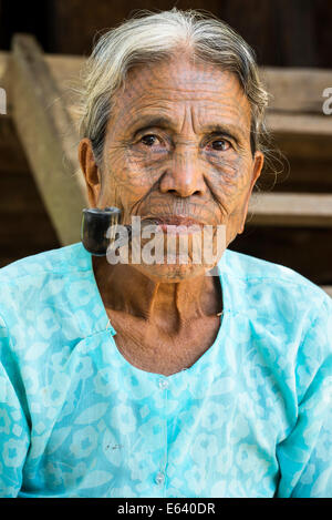 Donna del mento persone appartenenti a una minoranza etnica, con un tradizionale tatuaggi facciali di fumare un tubo, l'ultima della loro natura, ritratto Foto Stock