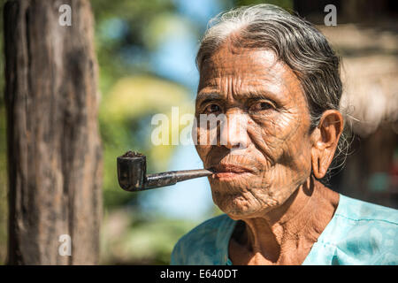 Donna del mento persone appartenenti a una minoranza etnica, con un tradizionale tatuaggi facciali di fumare un tubo, l'ultima della loro natura, ritratto Foto Stock