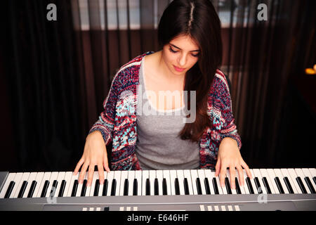 Giovane bella donna che gioca sul piano a casa Foto Stock