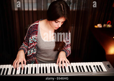 Giovane bella donna che gioca sul piano a casa Foto Stock