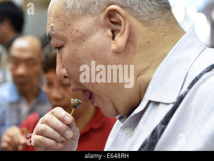 Hong Kong, Cina. 14 Ago, 2014. Un visitatore cerca Hong Kong cibo tipico durante il venticinquesimo Food Expo di Hong Kong, Cina del Sud, 14 agosto 2014. L'Expo ha dato dei calci a fuori il giovedì e visitatori potrebbe essere introdotto in una vastissima gamma di prodotti alimentari da parte di fornitori di qualità provenienti da tutto il mondo. Credito: Lui Siu Wai/Xinhua/Alamy Live News Foto Stock