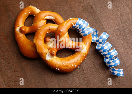 Due tipici pretzel bavarese di bianco e blu con streamer su uno sfondo marrone Foto Stock