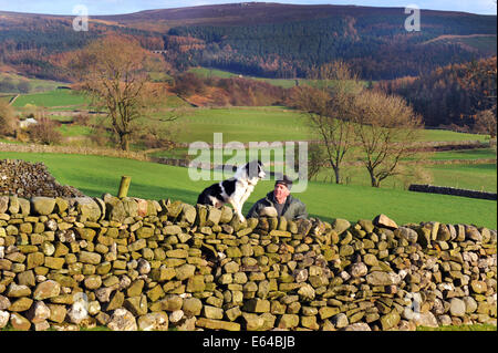 Allevatore ovino con il suo cane su una parete di stalattite, Yorkshire Dales. Foto Stock