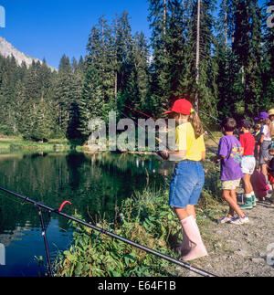 Bambini angling a Les Mines d'o lago di Morzine resort Savoy sulle Alpi francesi Francia Foto Stock