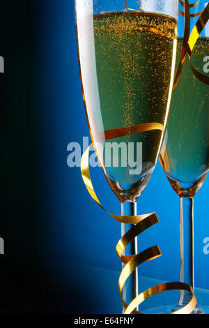 Coppia di bicchieri di champagne con streamer oro su sfondo blu Foto Stock