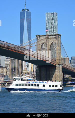 New York ferry passando sotto il ponte di Brooklyn come crociere lungo la East River. Foto Stock