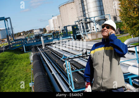 Ingegnere in hard-hat con tubazioni all'interno della raffineria di petrolio Foto Stock