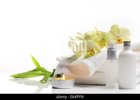 Spa ancora in vita con asciugamano, candele accese e fiore su sfondo bianco. Foto Stock