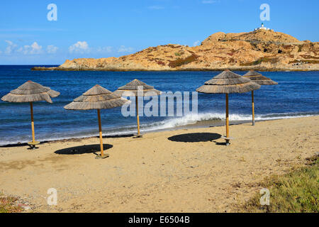 Ombrelloni di paglia sulla spiaggia cittadina, isola Île de la Pietra sul retro, l'Île Rousse Balagne in Corsica, Francia Foto Stock