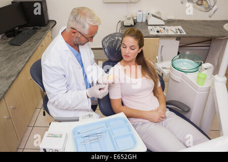 Dentista parlando con il paziente in una sedia che mostra il modello di bocca Foto Stock
