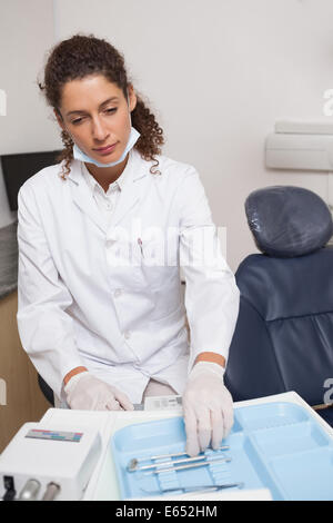 Dentista di prelevare un utensile a fianco della sedia Foto Stock