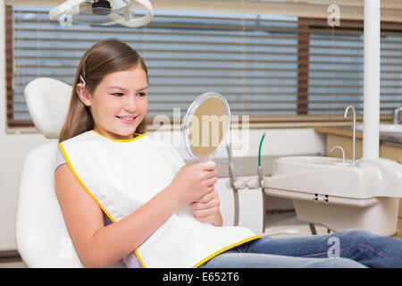 Little Girl holding specchio nella sedia dentisti Foto Stock