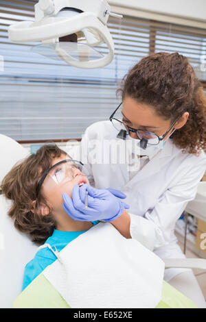 Dentista pediatrico esaminando un po' i ragazzi di denti in sedia dentisti Foto Stock