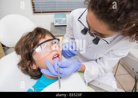 Dentista pediatrico esaminando un po' i ragazzi di denti in sedia dentisti Foto Stock