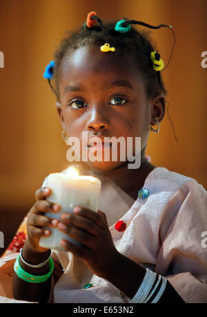 La ragazza (3 anni) tenendo la candela in una chiesa cattolica a Kaolack, Senegal Africa Foto Stock