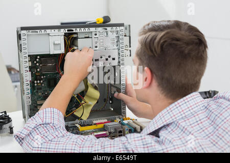 Giovane tecnico che lavora su computer rotto Foto Stock