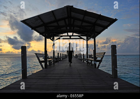 Donna che cammina sul pontile in legno di sunrise, isola del Borneo, Stato di Sabah, Malesia, sud-est asiatico Foto Stock