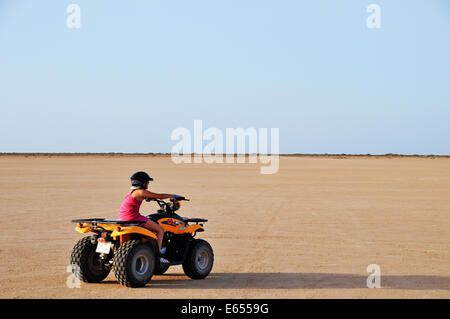 Ragazza giovane accelerando su ATV moto quad nel deserto, Tunisia, Nord Africa Foto Stock