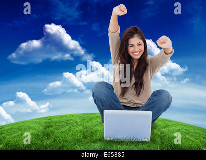 Immagine composita della donna guarda dritto come la celebra davanti al suo computer portatile Foto Stock