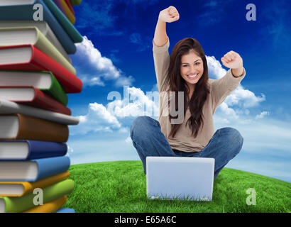 Immagine composita della donna guarda dritto come la celebra davanti al suo computer portatile Foto Stock