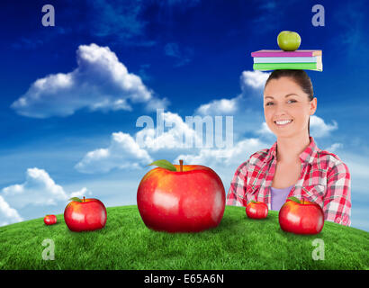 Immagine composita di pretty studente in possesso di un apple e libri sulla sua testa Foto Stock