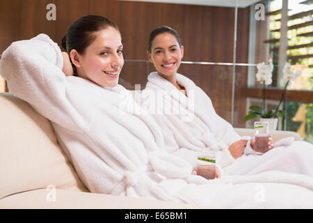 Donna sorridente in accappatoi seduta sul lettino Foto Stock