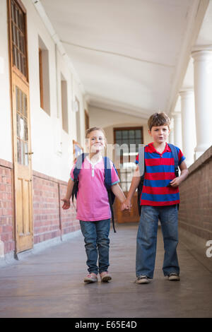 Carino alunni tenendo le mani in corridoio Foto Stock