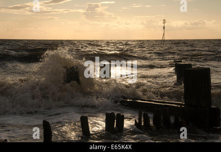 Onde che si infrangono sulle groyne sulla spiaggia a Hunstanton, Norfolk Foto Stock