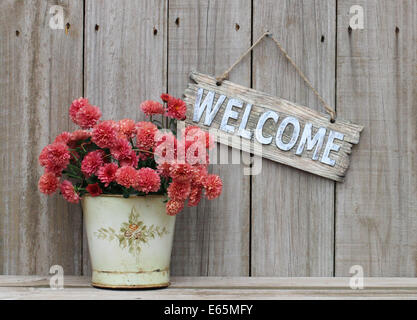 Rustico segno di benvenuto appeso a spiovente recinzione di legno accanto al vaso di fiori - autunno mamme Foto Stock