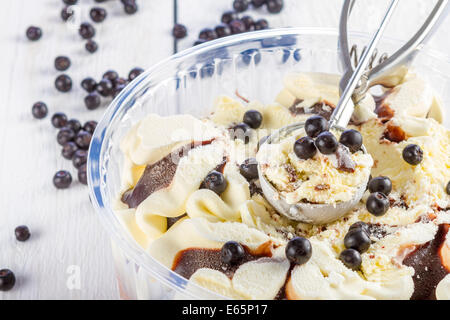 Vaniglia e gelato al cioccolato con blackberry scoop raccolto fuori di un contenitore sul bianco sullo sfondo di legno Foto Stock