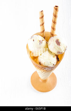 Gelato alla vaniglia con wafer nella tazza bianca su sfondo di legno Foto Stock