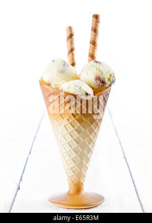 Gelato alla vaniglia con wafer nella tazza bianca su sfondo di legno Foto Stock