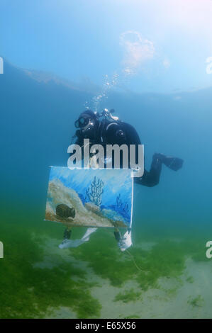 Artista assistente nuota con il quadro dipinto da l'acqua, l'artista artista subacquea Yuriy Alexeev (Yuri Alekseev). Foto Stock