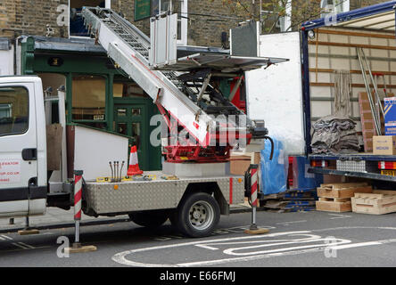 Traslochi uomini tramite ascensore per sollevare possedimenti al primo piano finestra, Londra Foto Stock