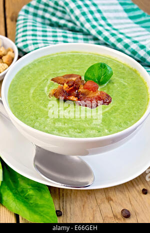 Zuppa verde purea in una ciotola bianca con spinaci e carne alla brace, igienico, cracker, cucchiaio su tavole di legno sfondo Foto Stock