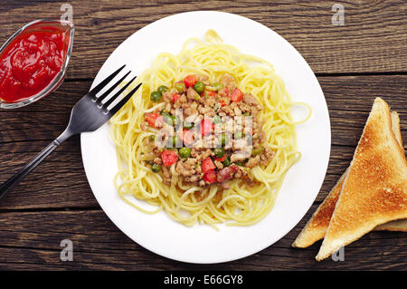 Spaghetti con carne macinata e verdure su vintage tavolo in legno. Vista superiore Foto Stock