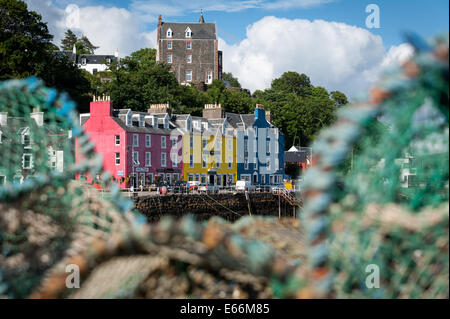 Gli edifici colorati sul lungomare a Tobermory, Isle of Mull, Scozia visto incorniciata da lobster pot. Foto Stock